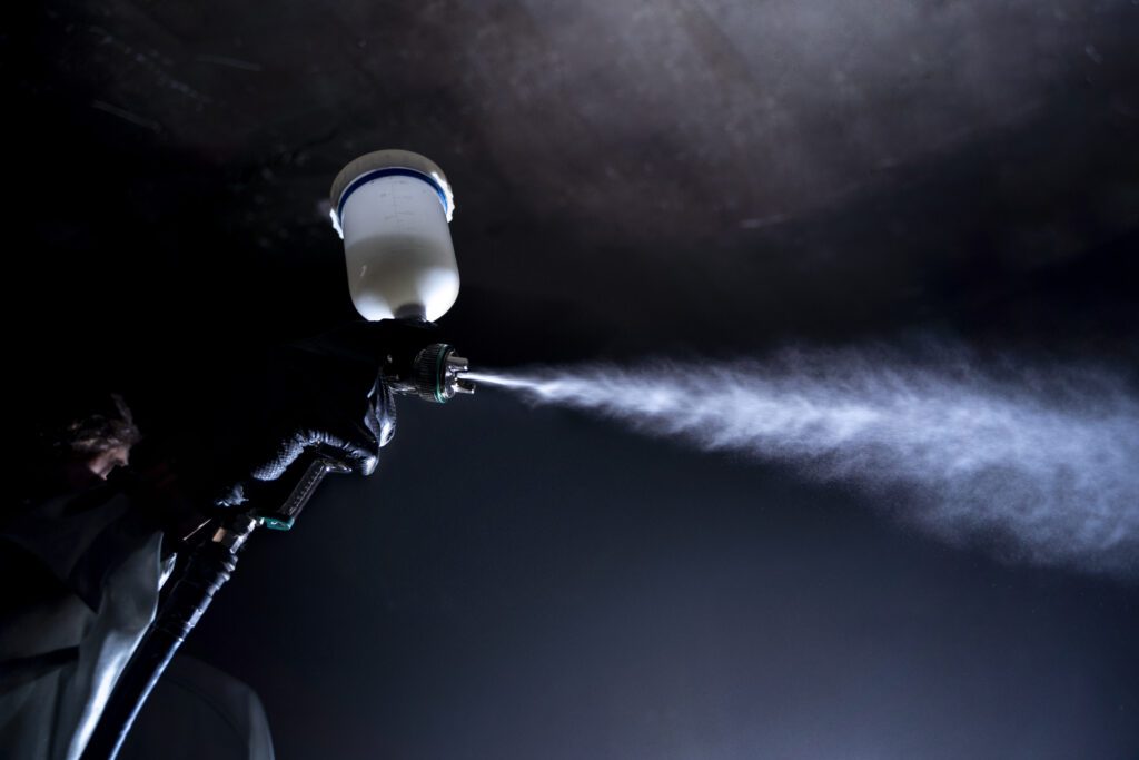 low angle worker spraying powder paint from gun